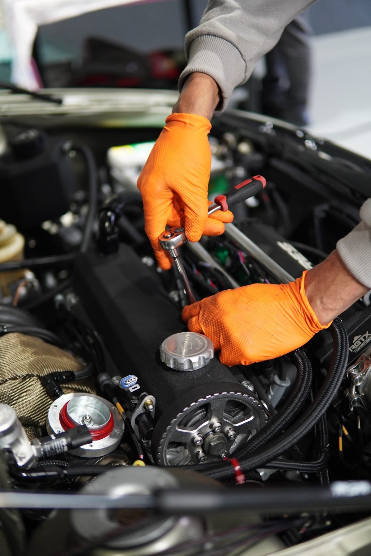 Mãos com luvas ajustando componente do motor com chave de fenda